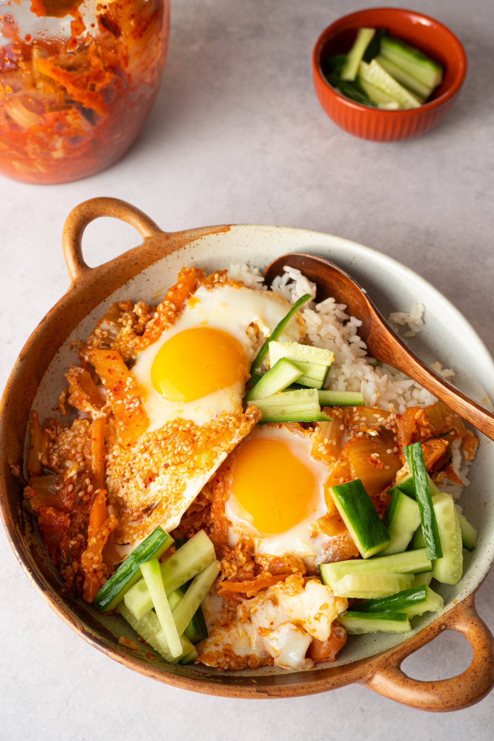 A plate of kimchi fried eggs with rice, a traditional Korean dish, featuring the combination of spicy kimchi and fried eggs, garnished with green onions and sesame seeds.