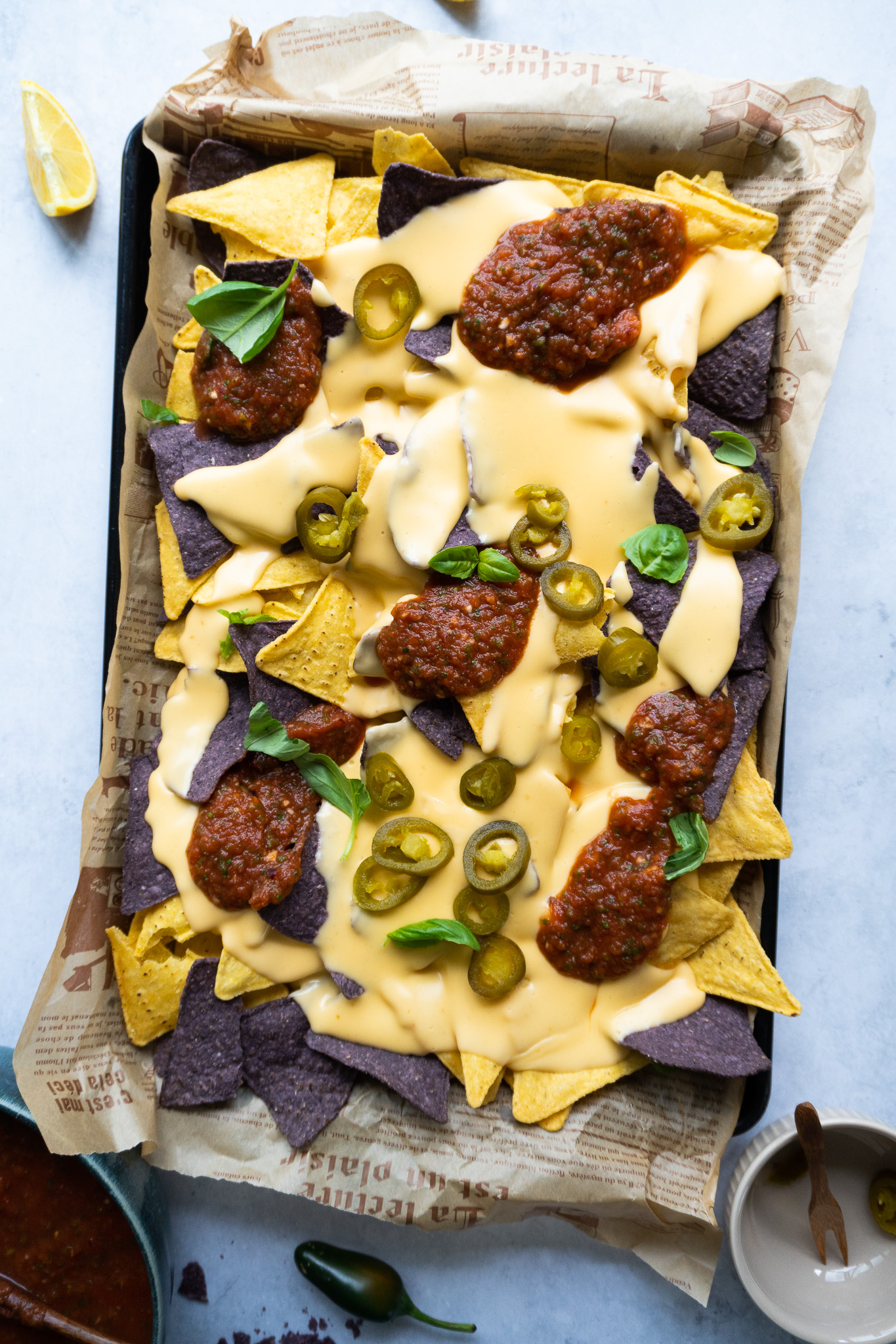 Classic Nachos with Homemade Cheese Sauce - Irresistible Golden and purple corn tortilla chips loaded with homemade cheese sauce, jalapeños, and fresh toppings.