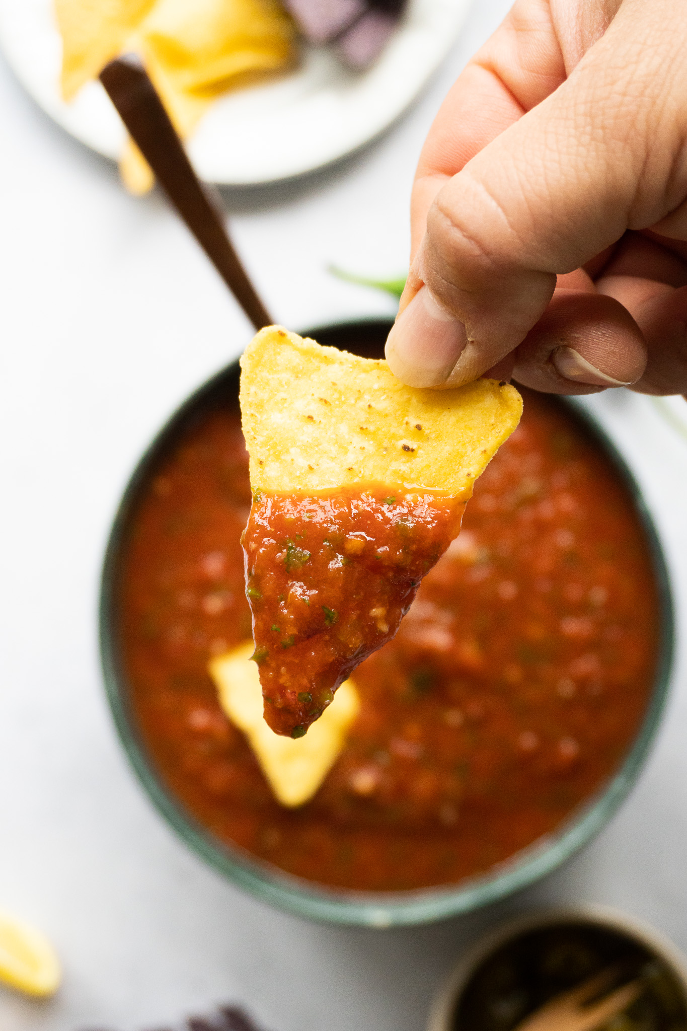 An enticing image of homemade tomato salsa, replicating the famous Costco recipe. Ripe tomatoes, onions, garlic, and aromatic spices create a harmonious blend of textures and tastes. sat on a tortilla chips dipped in salsa