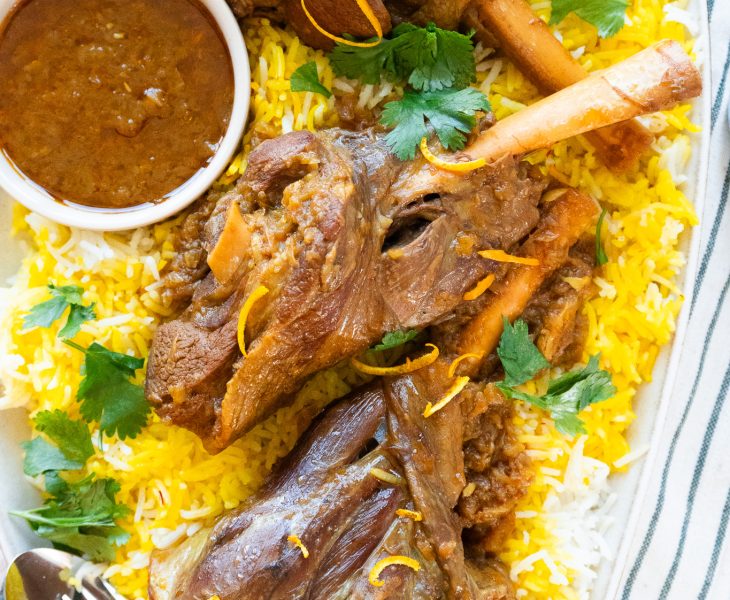 Persian Lamb Shank (Mahiche) - Slow-cooked tender lamb shank served with aromatic cooking liquid and garnished with fresh herbs.